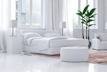 a bedroom with white furniture and large windows